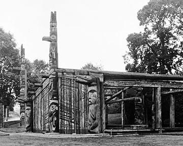 Nuu-chah-nulth (Huu-ay-aht) House Posts in front of a Haida House