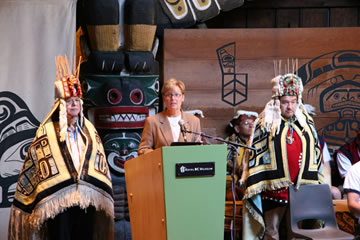 Pauline Rafferty, Présidente-directrice-générale du Musée royal de la C.-B., avec le chef Tony Hunt à sa gauche et le chef Peter Knox à sa droite, s’adressant au public lors de l’inauguration du site web du parc Thunderbird le 18 mai 2006.
