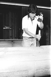 Richard Hunt sculpting a totem Pole using a hand maul and chisel